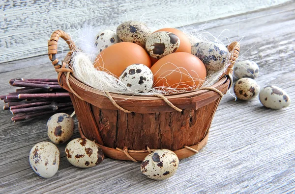 Verschillende soorten eieren in een mand op een oude houten achtergrond — Stockfoto