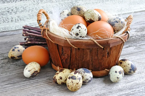 Verschillende soorten eieren in een mand op een oude houten achtergrond — Stockfoto