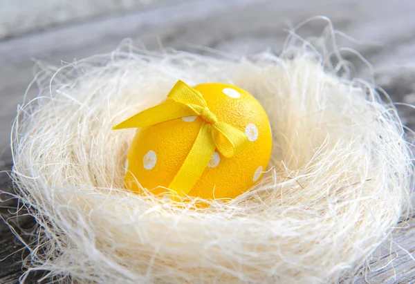 Huevo amarillo de Pascua está en un nido sobre un viejo fondo de madera —  Fotos de Stock