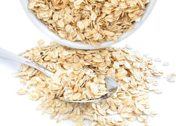 Oat flakes in bowl and spoon on white background — Stock Photo, Image
