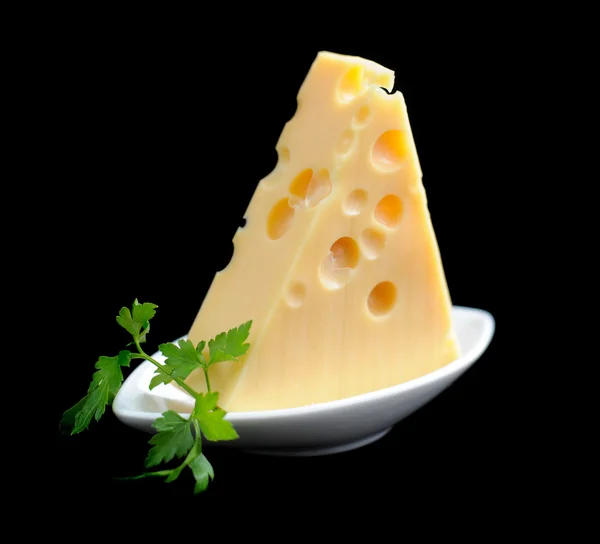 Pedazo de queso en un plato aislado sobre un fondo negro —  Fotos de Stock