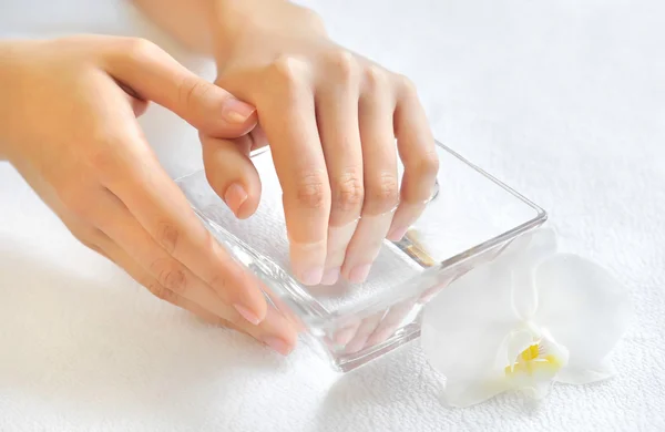 Donna mani in ciotola di vetro con acqua su un asciugamano bianco — Foto Stock