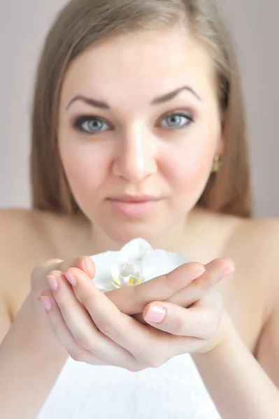 Mãos bonitas da mulher com flor branca do orchid. O foco está em uma mão — Fotografia de Stock