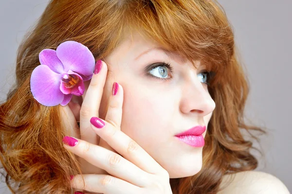 Schönes Mädchen hält Orchideenblume in ihren Händen — Stockfoto