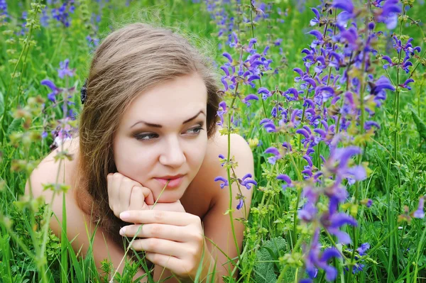 Mooie jonge vrouw in violette bloemen buitenshuis — Stockfoto