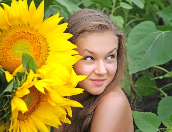 Junge schöne Frau in einem Sonnenblumenfeld — Stockfoto