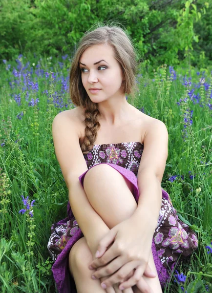 Mooie jonge vrouw in violette bloemen buitenshuis — Stockfoto