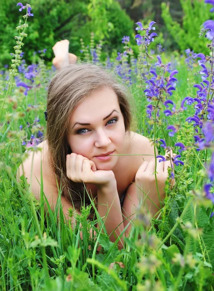 Mooie jonge vrouw in violette bloemen buitenshuis — Stockfoto