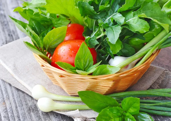 Frisches Gemüse und Grünzeug liegen in einem Korb auf altem Holzgrund — Stockfoto