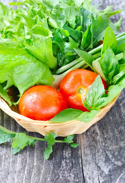 Verduras frescas y vegetación están en una canasta sobre un fondo de madera viejo — Foto de Stock