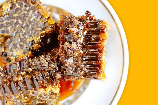 Panales dulces con miel en plato sobre fondo amarillo — Foto de Stock