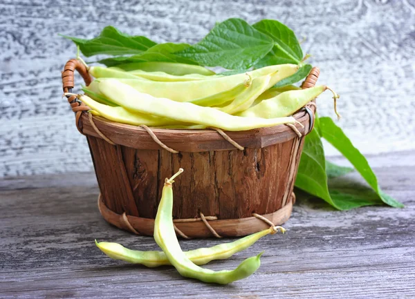 Haricots rouges jaunes dans un panier sur une vieille table en bois — Photo