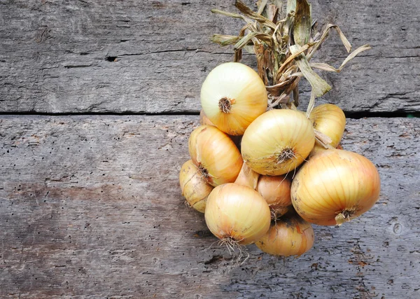 Bunch of onions on an old wooden background — Stock Photo, Image
