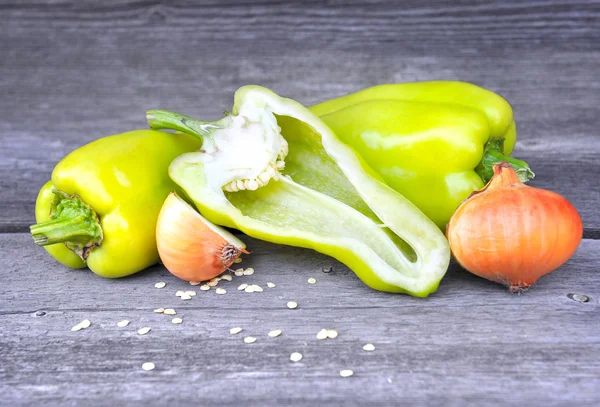 Verse zoete groene paprika en uien op een oude houten tafel — Stockfoto