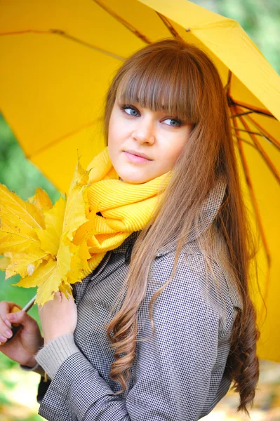 Schöne junge Frau mit einem gelben Regenschirm — Stockfoto