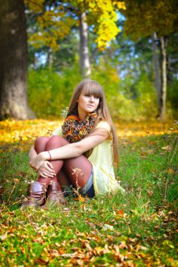 Genç ve güzel bir kadın sonbahar parkında dinleniyor.