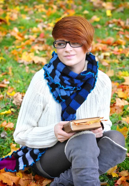 Hermosa chica con libro en el parque de otoño — Foto de Stock