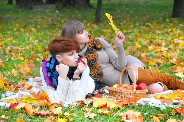 Young girls in the autumn park sitting on the grass — Stock Photo, Image