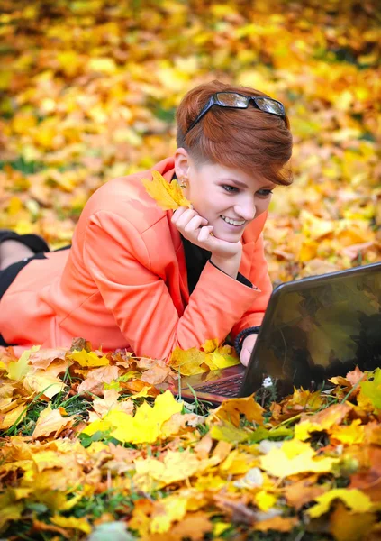 Femme mignonne avec ordinateur portable dans le parc d'automne — Photo
