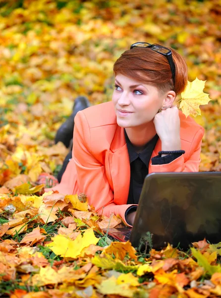 Nette Frau mit Laptop im Herbstpark — Stockfoto