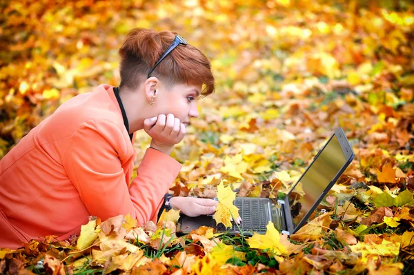 Mujer linda con portátil en el parque de otoño — Foto de Stock