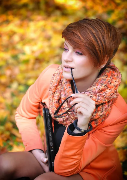 Leuke vrouw met laptop in de herfst park — Stockfoto