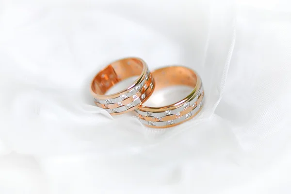 Dva snubní zlaté snubní prsteny jsou na pozadí bílý závoj — Stock fotografie
