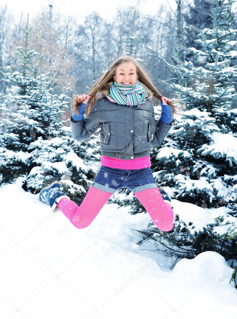 Happy young beautiful woman jumping in winter park