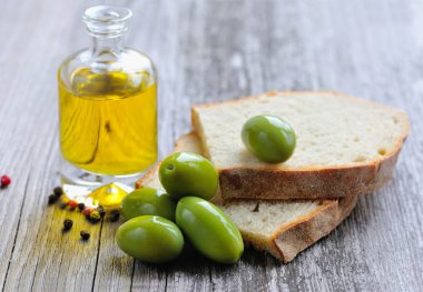 Yeşil zeytinli ekmek parçalarını ve ahşap masa üzerine bir şişe