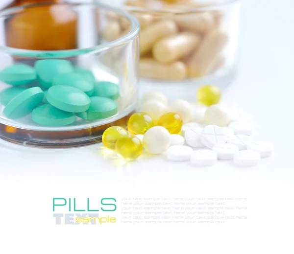 Heap of colorful pills and glass on a white background — Stock Photo, Image