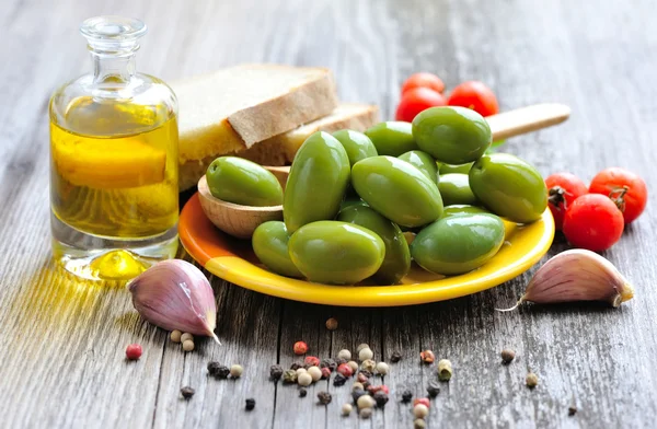 Olive verdi con spezie, pane e olio su fondo di legno — Foto Stock