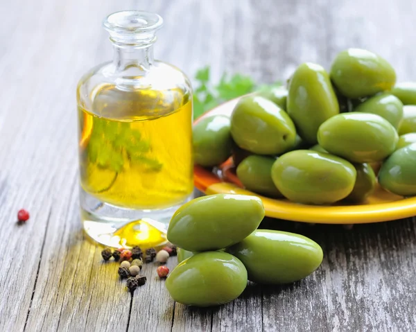 Groene olijven met olieverf op houten achtergrond fles — Stockfoto