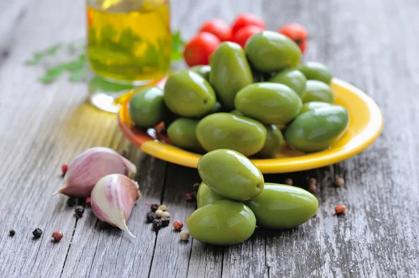 Grüne Oliven mit Knoblauch und Pfeffer auf einem hölzernen Hintergrund — Stockfoto