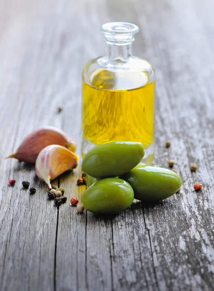 Olive verdi con bottiglia di olio su fondo di legno — Foto Stock