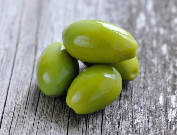 Grüne Oliven auf einem hölzernen Hintergrund — Stockfoto