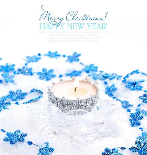 Vela de Navidad con copos de nieve azules en la nieve — Foto de Stock