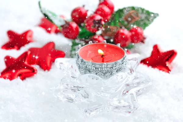 एक क्रिसमस मोमबत्ती बर्फ पर सजावट के साथ है — स्टॉक फ़ोटो, इमेज