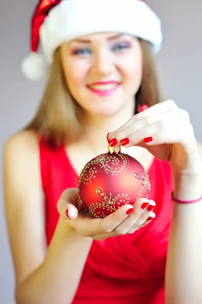 Closeup για Χριστούγεννα μπάλα στο χέρι της γυναίκας με κόκκινο φόρεμα — 스톡 사진