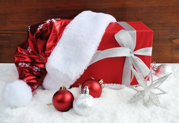 Santa Claus hat with christmas gift and decorations on snow — Stock Photo, Image