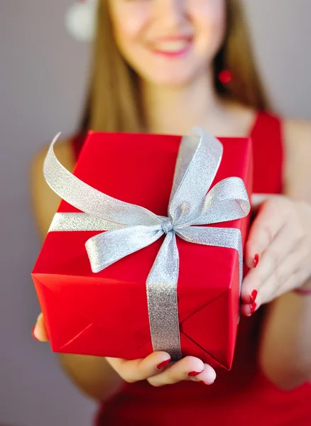 Woman holding out red Christmas gift on the palm of her hand towards the viewer, close up of her hand with selective focus Stock Photo