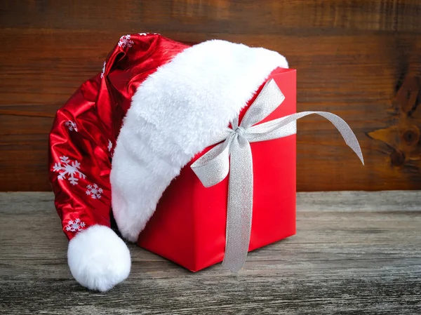 Cappello Babbo Natale con regalo di Natale rosso su sfondo di legno — Foto Stock