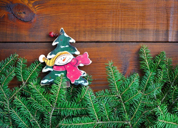 Ramas de abeto con muñeco de nieve y decoraciones navideñas en madera —  Fotos de Stock