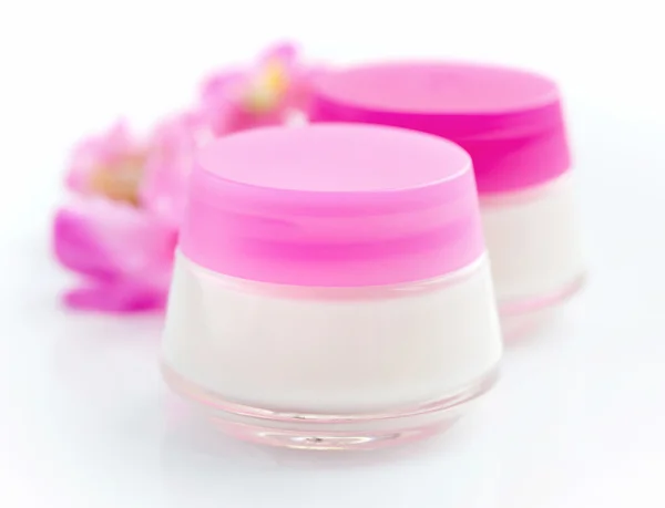 Cremes cosméticos e flores rosa isoladas sobre fundo branco — Fotografia de Stock
