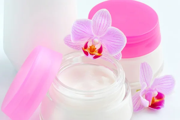 Face creams and beautiful orchid flowers on white background — Stock Photo, Image