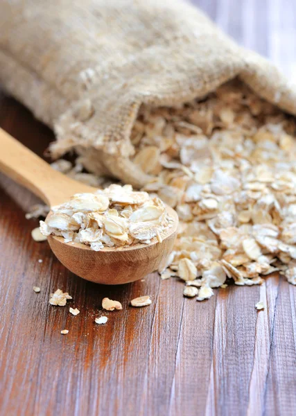 Oat flakes in wooden spoon on wooden background — Stock Photo, Image