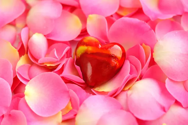 Corazón decorativo sobre pétalos de rosa rosa, fondo romántico — Foto de Stock