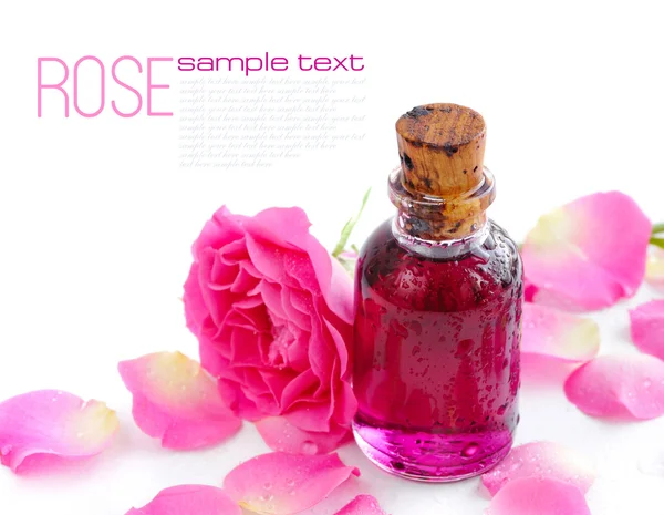 Butelka olejku i różowa róża na białym tle — Zdjęcie stockowe