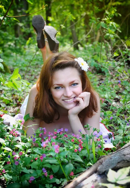 Mooie jonge vrouw in het bos met Lentebloemen — Stockfoto