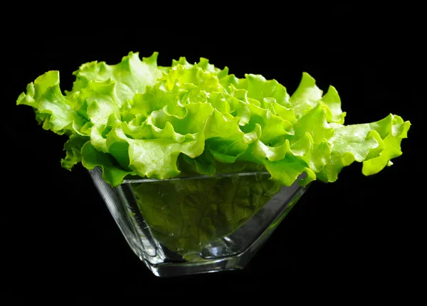 Salada verde fresca em um prato de vidro em fundo preto — Fotografia de Stock
