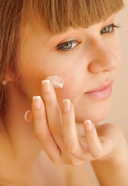 El rostro hermoso de la mujer joven con la crema cosmética en la mejilla. Concepto de cuidado de la piel — Foto de Stock